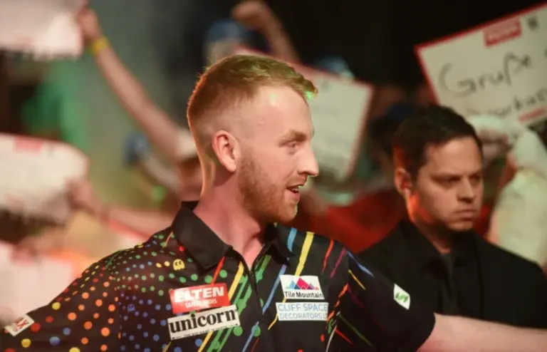 Adam Paxton beim Dartswerfen auf der Bühne