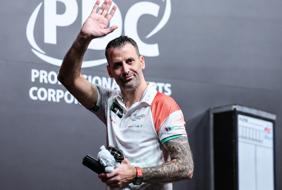 György Jehirszki hebt beim PDC World Cup of Darts 2025 auf der Bühne grüßend den Arm.