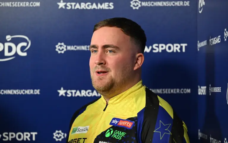 Luke Littler im gelb-blauen Dartstrikot vor einer Sponsorenwand bei der European Championship 2026.