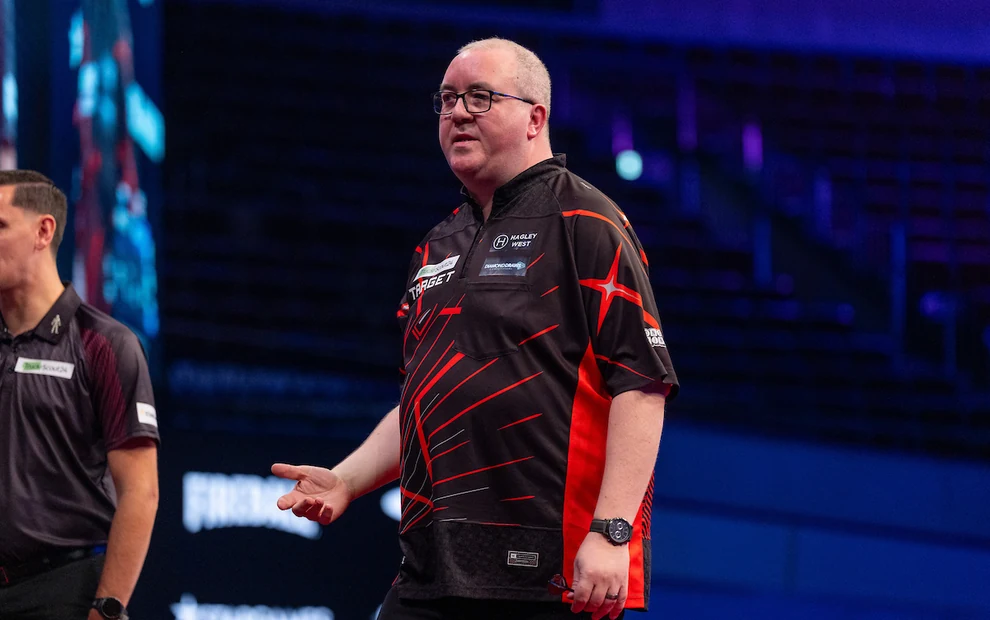 Stephen Bunting im schwarz-roten Darttrikot auf der Bühne eines PDC-Turniers mit ausgestreckter Hand.